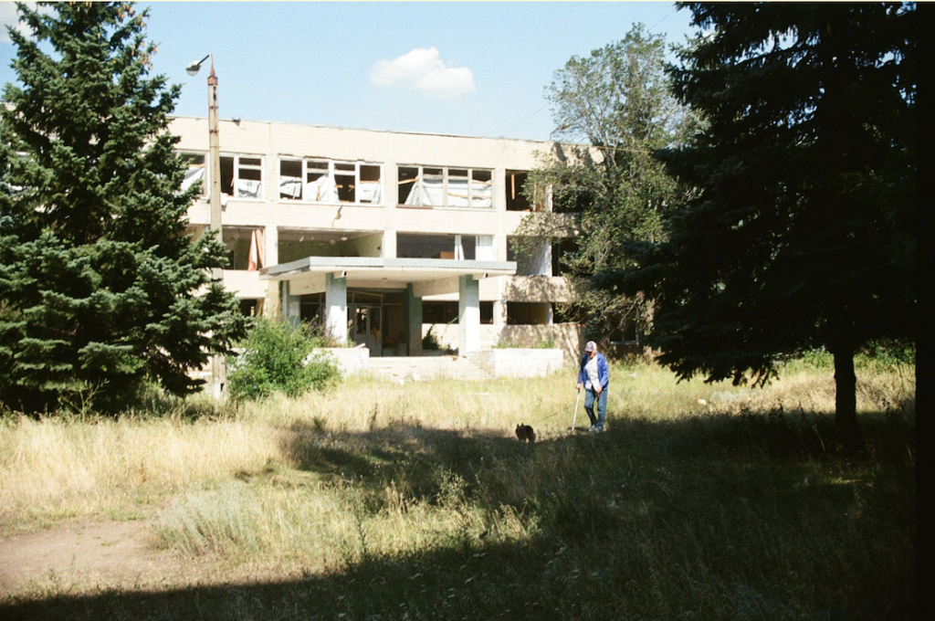 Un homme promène son chien devant une école détruite par une bombe aérienne guidée russe. Kramatorsk, août 2026. Yulia Kalaban pour JAMnews.